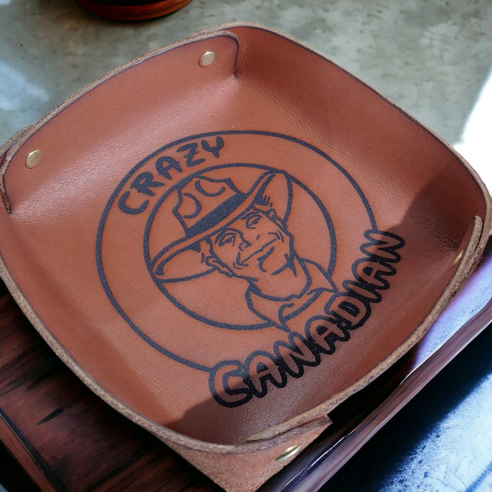 Crazy Canadian Dice Tray. Made of Vegetable Tanned Leather, hand-dyed a Medium Brown. Logo is Laser Engraved. 7″ x 7″