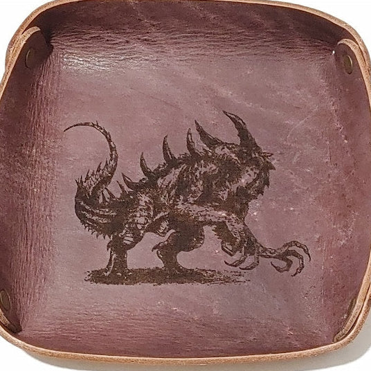 Fantasy Dice Tray  Made of Vegetable Tanned Leather, hand-dyed a Medium Brown.  Logo is Laser Engraved. 7″ x 7″  *Includes a standard set of 7 dice.